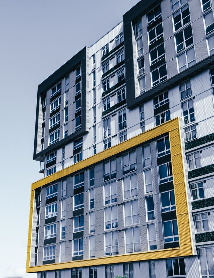 Low angle exterior of modern multistory residential building with creative geometric design ans symmetric windows against cloudless sky