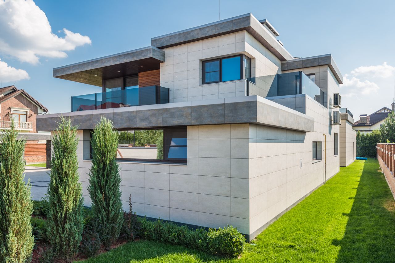 Contemporary two-story house with clean lines surrounded by green grass and blue sky.