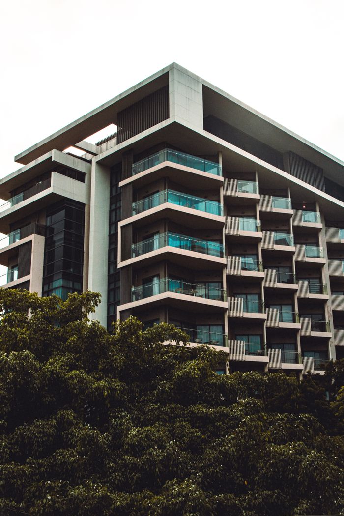 Low angle view of a modern residential building with balconies amidst greenery.